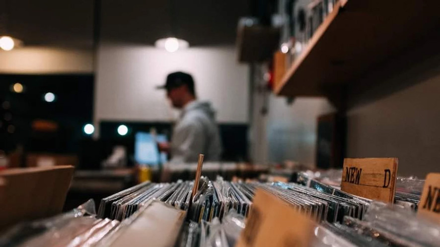 a dj looking through deep house and techno vinyl records at the local record store