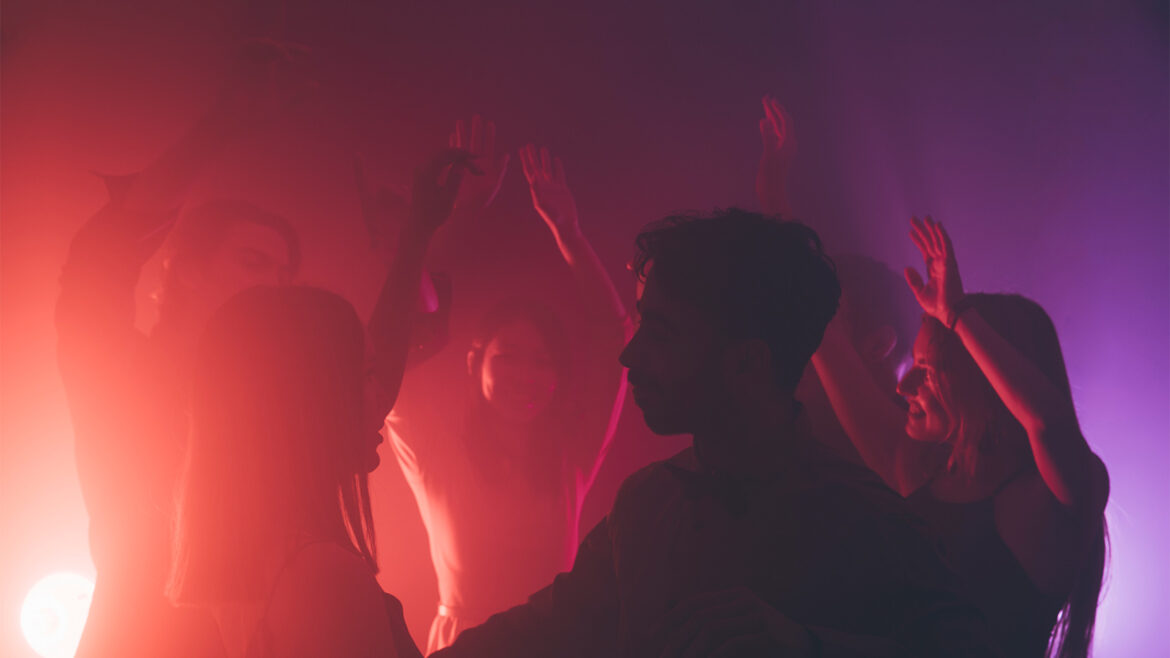 clubbers dancing in a nightclub with pink and purple lights and techno music